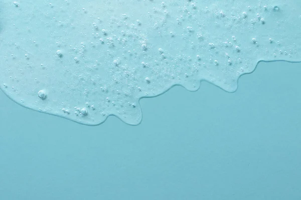 Fondo de gel cosmético con burbujas, goteando hacia abajo.Pastel color azul, espacio de copia para texto o diseño.Vista superior, superficie líquida antibacteriana.Bueno como fondo o maqueta. — Foto de Stock