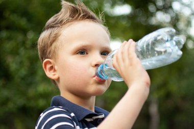 Havalı çocuk plastik şişeden su içiyor..
