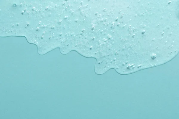 Background from cosmetic gel with bubbles,dripping down.Light blue color,copy space for text or design.Top view,antibacterial liquid surface.Good as background or mockup.