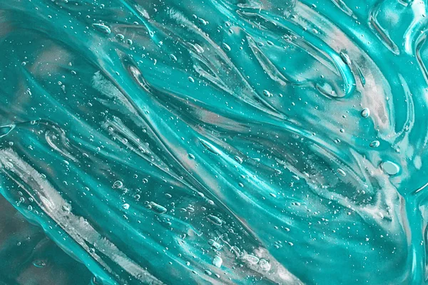Siero turchese ondulato con bolle sullo sfondo verde.Cosmetici striscio di aloe vera o gelatina antibatterica.Buono come mockup con spazio copia.. — Foto Stock