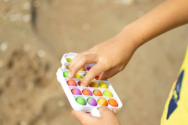 Criança brinca com novo brinquedo de silicone - pop-lo na praia.Simples covinha no quadro plástico.Nova tendência de verão para crianças e adultos. — Fotografia de Stock