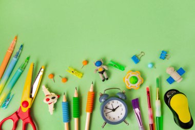 Yeşil arka planda farklı okul malzemeleri. Okul konseptine geri dön, üst görüş. Fotokopi alanı olan yeşil arkaplan..