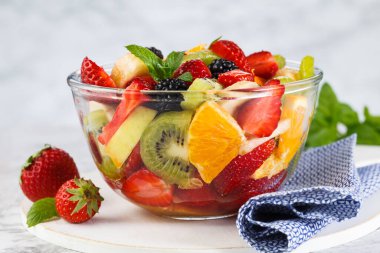 Sağlıklı taze meyve salatası gri arka planda bir kasede.