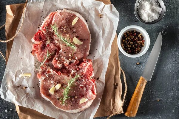 stock image Two raw pork steaks grey stone background with rosemary and spices. Top view, copy space