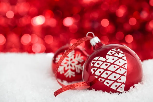 Kerstballen met geschilderde hart en sneeuwvlok tegen rode hol — Stockfoto