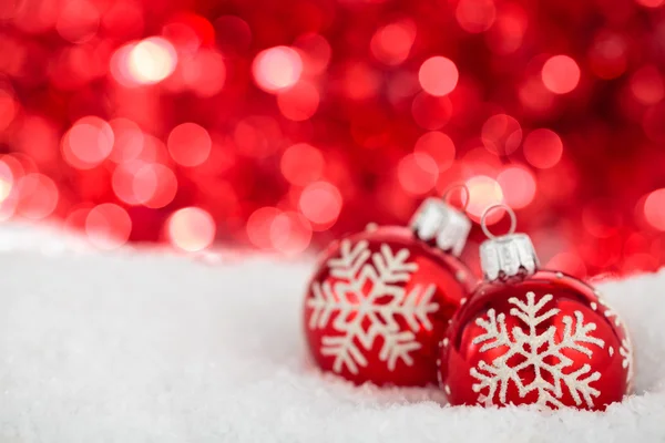 Weihnachtskugeln mit bemalten Schneeflocken gegen rote Feiertage Stockbild