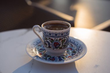 Kahve fincanındaki Türk kahvesi, bir kafede, sokaktaki bir masada ulusal bir süs eşyası. Günbatımı güneşi