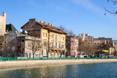 Bükreş, Romanya, 13 Şubat 2021 - Romanya 'nın başkenti Dambovita nehri yakınlarındaki büyük eski ağaçlar ve eski binalarla manzara ve güneşli bir kış gününde Romanya' nın Bükreş 'in merkezinde açık mavi gökyüzü