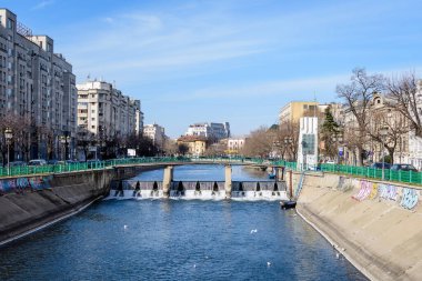 Bükreş, Romanya, 13 Şubat 2021 - Romanya 'nın başkenti Bükreş' te güneşli bir kış gününde küçük köprü, Dambovita nehri yakınlarındaki eski binalar ve açık mavi gökyüzü