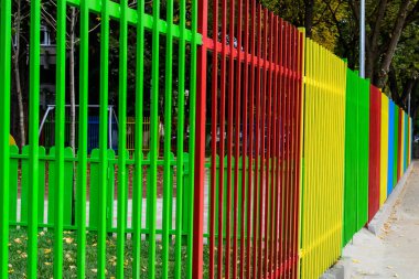 Romanya 'nın Bükreş kentinde güneşli bir yaz gününde, karışık plastik ve metalik oyuncaklar ve malzemelerle dolu bir çocuk parkındaki renkli çitler