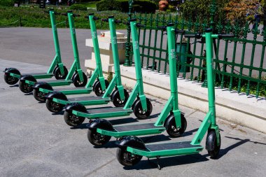 Bükreş, Romanya, 10 Nisan 2021: Şehir merkezinde vatandaşlar ve turistler için özel mobil uygulama kullanılarak kiralık elektrikli scooterlar
