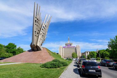 Bükreş, Romanya - 15 Mayıs 2021: Güneşli bir bahar gününde merkezde Sovyet Sosyalist gerçekçiliği tarzında Kanatlar anıtı ve Özgür Basın Evi 'nin (Casa Presei Libere) ana binası