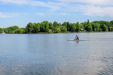 Bükreş, Romanya - 15 Mayıs 2021: Romanya 'nın başkenti Bükreş' te güneşli bir bahar gününde Herastrau Gölü 'ndeki beyaz tekne ve Kral I. Michael Park' taki (Herastrau) büyük yeşil ağaçlarla manzara