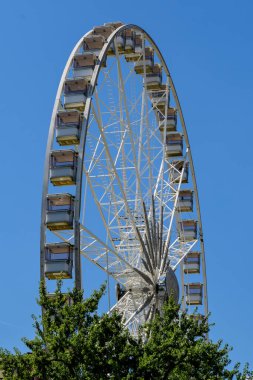 Güneşli bir yaz gününde Macaristan 'ın Budapeşte kentindeki Erzsebet Meydanı' nda dev beyaz dönme dolaba sahip renkli çocuklar oyun parkı.
