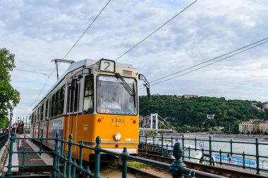 Budapeşte, Macaristan, 6 Ağustos 2019: Güneşli bir yaz gününde eski şehir merkezinde, sokaklarda ve toplu taşıma sisteminde seyahat eden yolcular için tarihi sarı tramvay