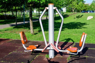 Romanya 'nın Bükreş kentinde güneşli bir bahar gününde, bir şehir parkındaki spor ve etkinlikler için açık hava fitness makinesi