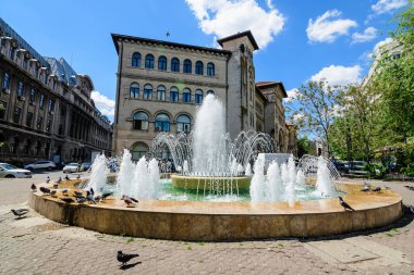 Bükreş, Romanya - 6 Mayıs 2021: Su çeşmesi ve İon Mincu Mimarlık Üniversitesi (Universitatea de Arhitectura si Urbanism Ion Mincu) Üniversite Meydanı (Piata Universitatii))