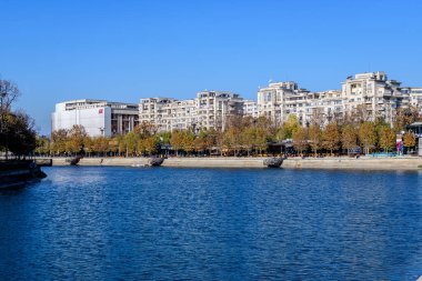 Bükreş, Romanya, 22 Kasım 2020: Romanya 'nın başkenti Bükreş' te güneşli bir sonbahar gününde Dambovita nehri, eski binalar ve sarı, turuncu ve kahverengi yapraklı manzara