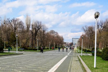 Bükreş, Romanya, 20 Mart 2021: Romanya 'nın başkenti Bükreş' te güneşli bir bahar gününde ana ara sokak ve göl kenarındaki büyük yeşil ağaçlarla manzara