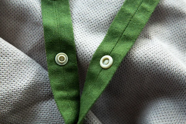 绿色网状辫子,扣子扣在浅灰织物的背景上 — 图库照片
