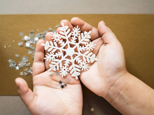 Eldivenli çocuk elleri mavi parlak kar tanesi oyuncağını tutuyor. Kış konsepti Yumuşak odaklı