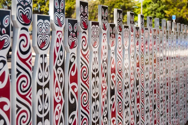 Fence with traditional Maori faces — Stock Photo, Image