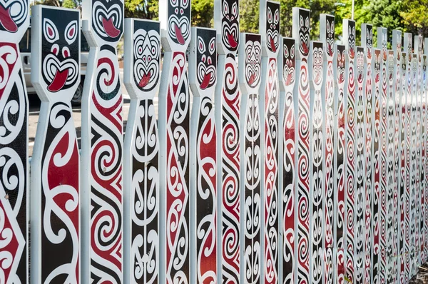 Fence with traditional Maori faces — Stock Photo, Image