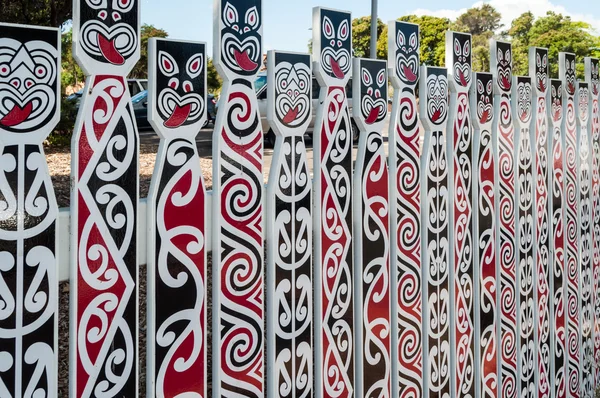 Fence with traditional Maori faces — Stock Photo, Image