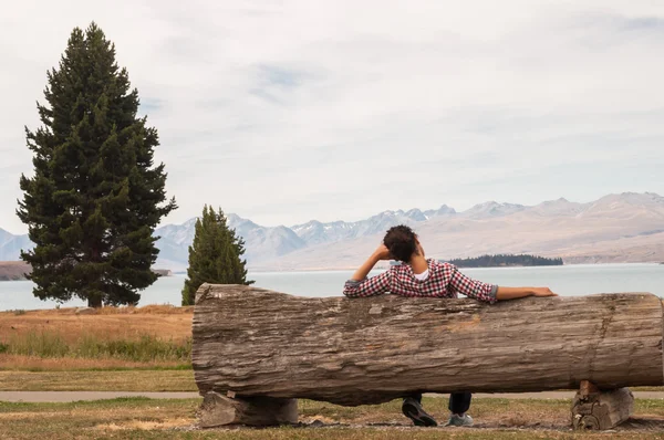 Woman sitting on a wooden bench beside a lake — Stock Photo, Image
