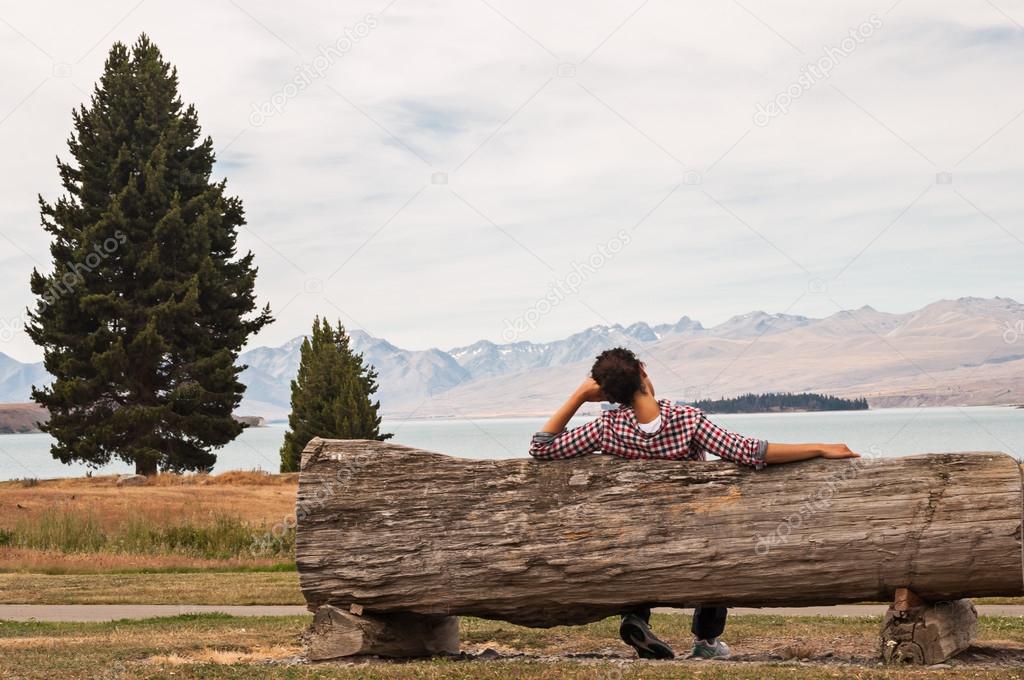 woman sitting on a wooden bench beside a lake