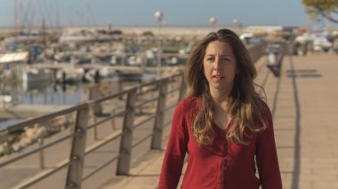 Beautiful blonde woman posing in harbor at sunny summer day.