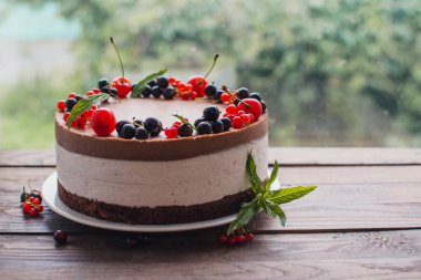 Ahşap bir masada dutlu kremalı pasta. Frenk üzümü ve kirazlı çikolatalı pasta. Doğum günü, düğün ve diğer tatiller için çilekli pasta..