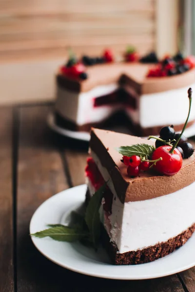 Mousse cake with berries on a wooden table. Chocolate cream cake with currants and cherries. Berry cake for birthday, wedding and other holidays.