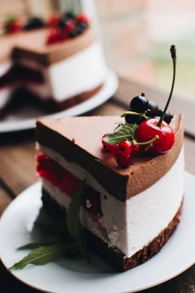 Mousse cake with berries on a wooden table. Chocolate cream cake with currants and cherries. Berry cake for birthday, wedding and other holidays.