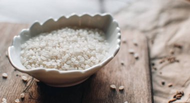 Ahşap zemin üzerinde beyaz pirinç bulunan organik gıda konsepti. Pirinçli kase.