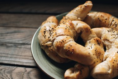 Freshly baked homemade croissants on wooden table. Selective focus. Fresh out of the oven. Breakfast or brunch concept.	