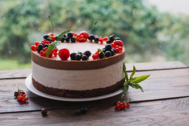 Ahşap bir masada dutlu kremalı pasta. Frenk üzümü ve kirazlı çikolatalı pasta. Doğum günü, düğün ve diğer tatiller için çilekli pasta..