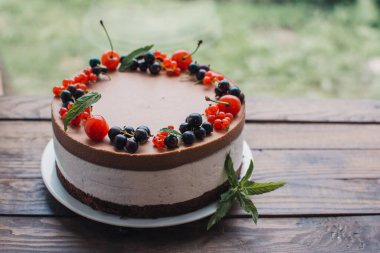 Ahşap bir masada dutlu kremalı pasta. Frenk üzümü ve kirazlı çikolatalı pasta. Doğum günü, düğün ve diğer tatiller için çilekli pasta..