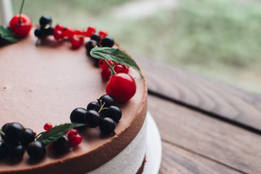 Ahşap bir masada dutlu kremalı pasta. Frenk üzümü ve kirazlı çikolatalı pasta. Doğum günü, düğün ve diğer tatiller için çilekli pasta..