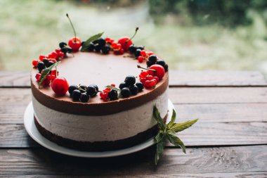 Ahşap bir masada dutlu kremalı pasta. Frenk üzümü ve kirazlı çikolatalı pasta. Doğum günü, düğün ve diğer tatiller için çilekli pasta..