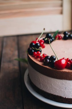 Ahşap bir masada dutlu kremalı pasta. Frenk üzümü ve kirazlı çikolatalı pasta. Doğum günü, düğün ve diğer tatiller için çilekli pasta..