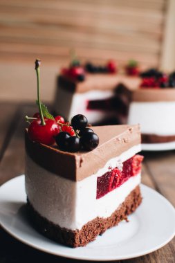 Ahşap bir masada dutlu kremalı pasta. Frenk üzümü ve kirazlı çikolatalı pasta. Doğum günü, düğün ve diğer tatiller için çilekli pasta..