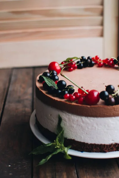 Mousse cake with berries on a wooden table. Chocolate cream cake with currants and cherries. Berry cake for birthday, wedding and other holidays.