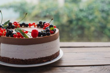 Ahşap bir masada dutlu kremalı pasta. Frenk üzümü ve kirazlı çikolatalı pasta. Doğum günü, düğün ve diğer tatiller için çilekli pasta..