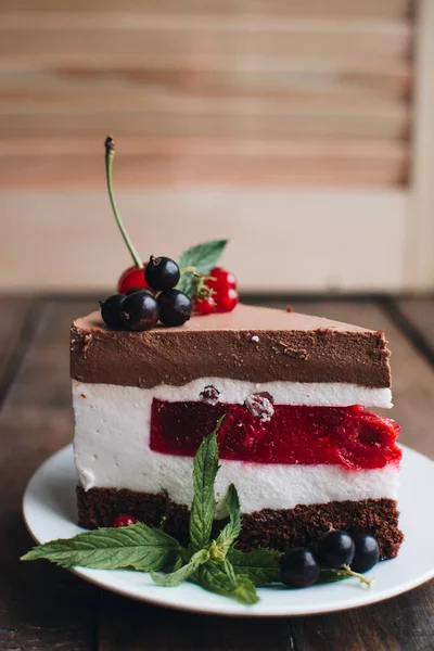 Mousse cake with berries on a wooden table. Chocolate cream cake with currants and cherries. Berry cake for birthday, wedding and other holidays.