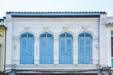 Tayland 'ın eski Phuket kasabasında Portekiz tarzında beyaz beton duvarda mavi renkli ahşap kemerli pencere..
