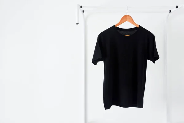 Siyah renkli t-shirt 'ün kapağı ahşap kumaş askıda asılı beyaz arkaplanda elbise askısı, boşluğu kopyala