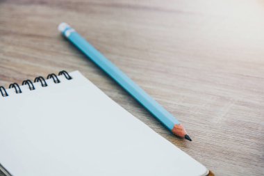 boş satırlı defteri ve mavi renkli kalemi kopyalama alanı olan tahta talble kara zemin üzerinde kapat (seçici odak)