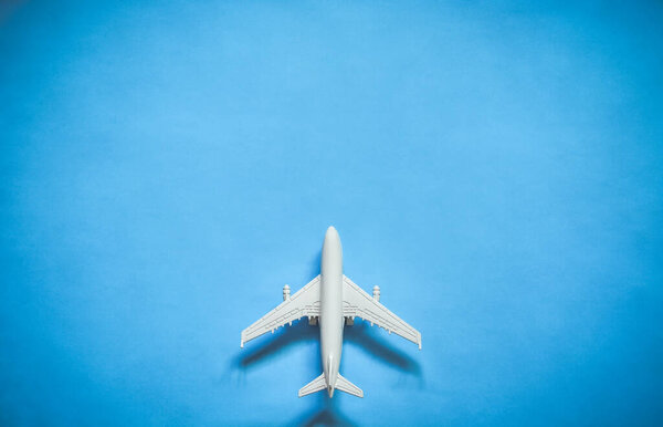 top view of white toy airplane model over blue color background with copy space, concept of travel