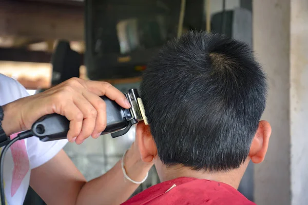 Female Hands Cutting Boy Hair Electric Hair Clipper Machine Home Stockfoto